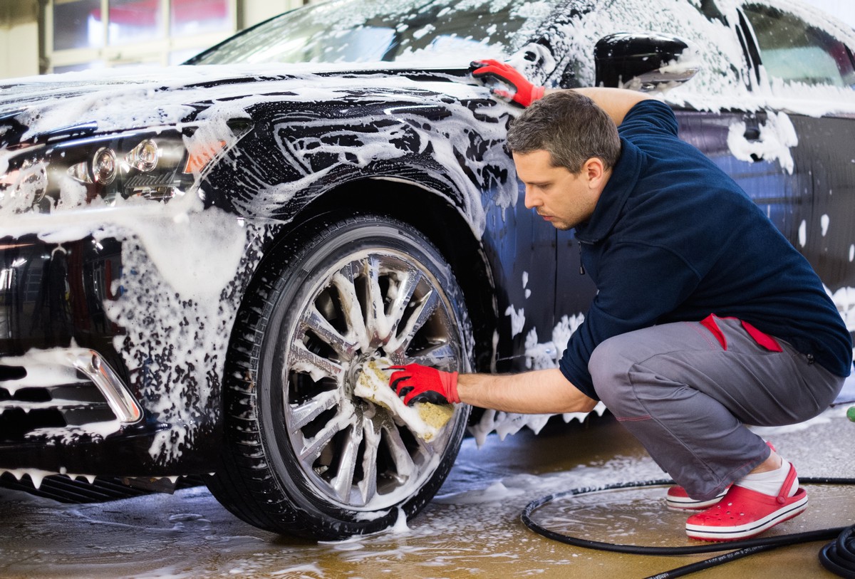 Un homme nettoie les roues d'une voiture